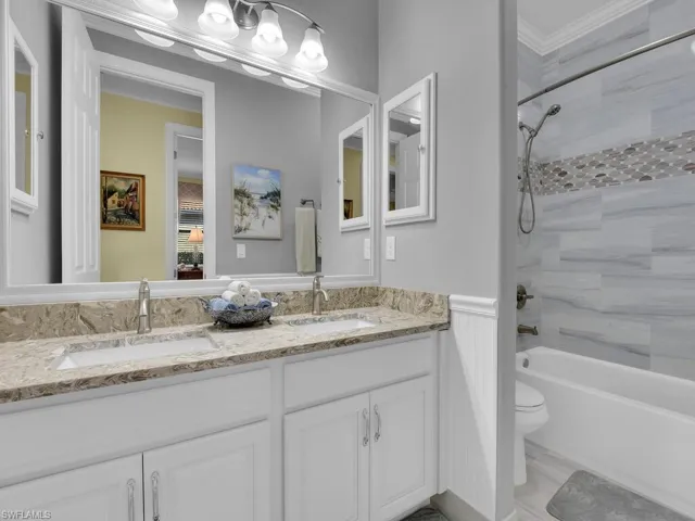Full bathroom with double vanity, bathing tub / shower combination, and ornamental molding