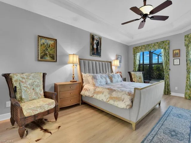 Bedroom with light wood-style floors, a raised ceiling, ornamental molding, ceiling fan, and access to exterior