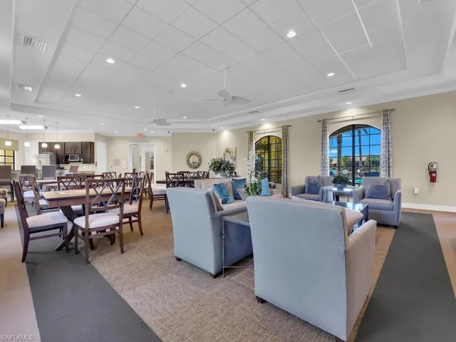 Carpeted living area with a tray ceiling, a paneled ceiling, a ceiling fan, and crown molding