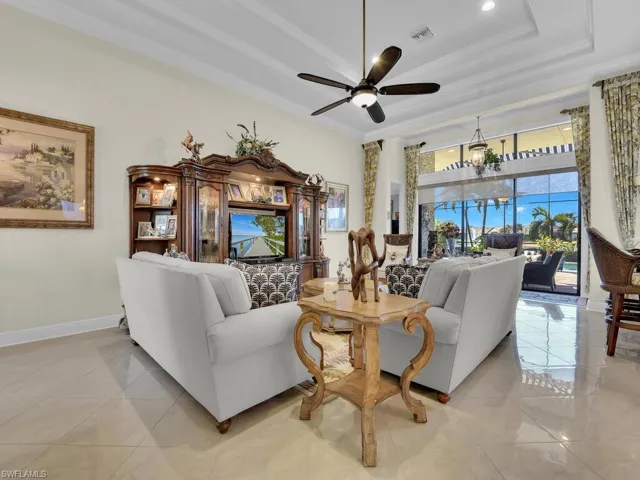 Living area featuring ceiling fan, crown molding, a tray ceiling, a chandelier, and recessed lighting