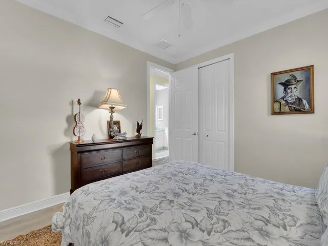 Bedroom featuring a closet, wood finished floors, ornamental molding, and ceiling fan
