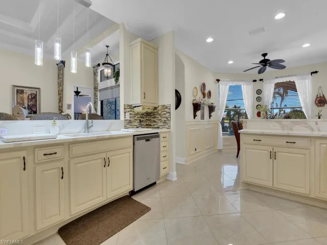 Kitchen with stainless steel dishwasher, cream cabinets, ceiling fan, crown molding, and tasteful backsplash