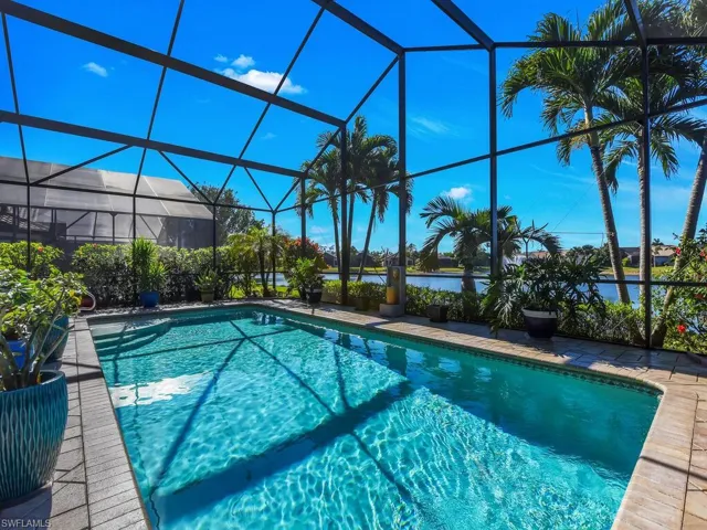 Outdoor pool featuring a water view, glass enclosure, and a patio