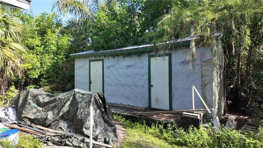 Storage shed with two entry doors, wrapped in house wrap, featuring a green trim roofline