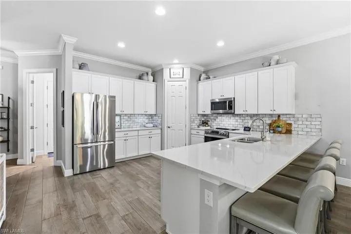 This chef-inspired kitchen boasts stainless steel appliances, sparkling quartz countertops with automatic under-cabinet lighting, a stunning subway tile backsplash, and 42-inch white cabinetry, combining elegance with practicality.