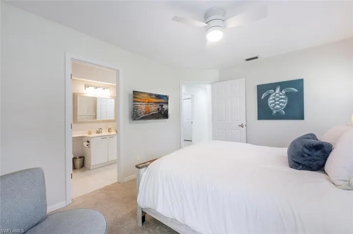 Carpeted bedroom with connected bathroom, sink, and ceiling fan