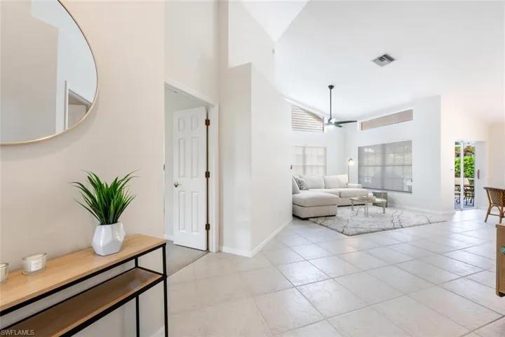 Living room with vaulted ceiling, light tile patterned floors, and ceiling fan