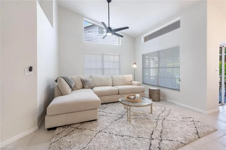 Living room featuring ceiling fan, high vaulted ceiling, and light tile patterned floors