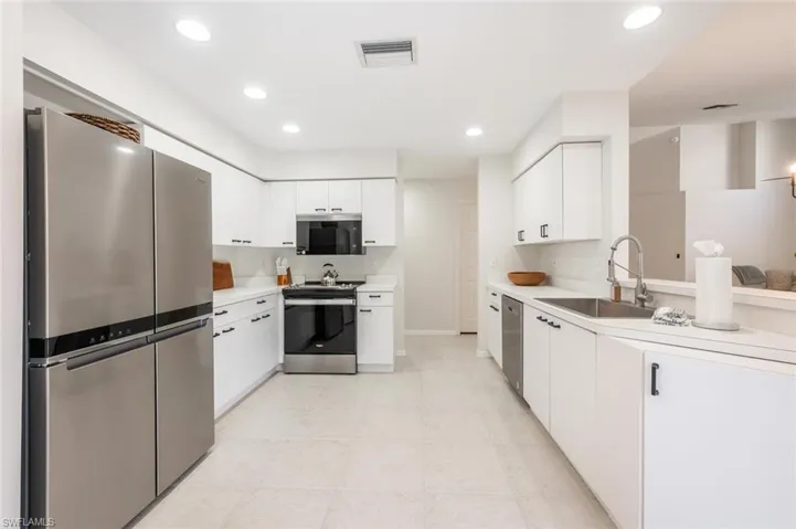 Kitchen with white cabinetry, stainless steel appliances, and sink