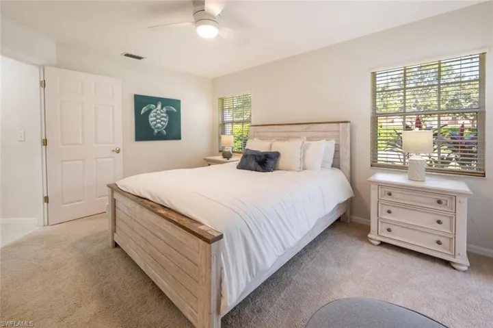 Bedroom featuring multiple windows, light colored carpet, and ceiling fan