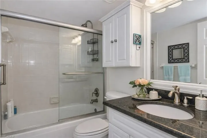 Bathroom with vanity and bath / shower combo with glass door
