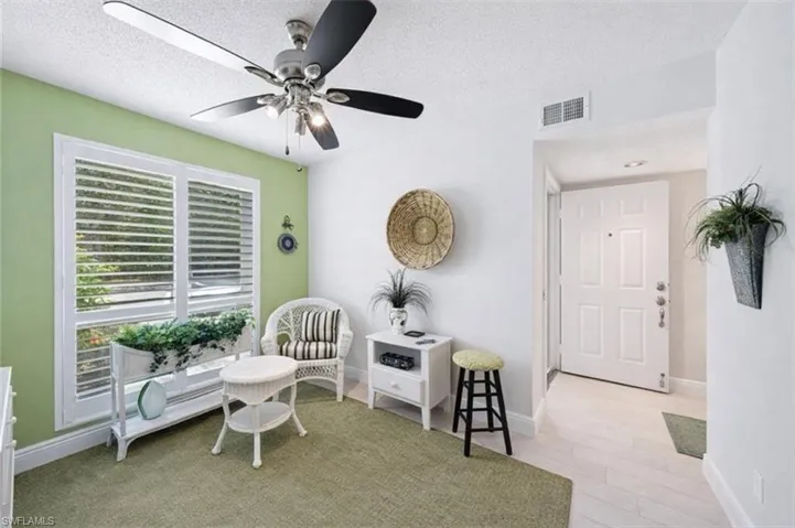 Sitting room featuring a textured ceiling, ceiling fan, and light wood-style flooring