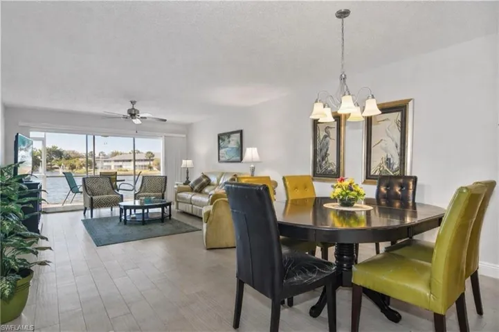 Dining space with a ceiling fan, hanging lights, a textured ceiling, and light wood-style flooring