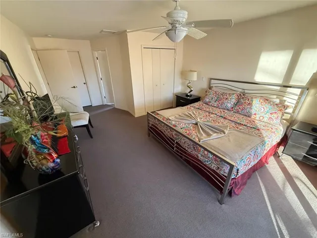 Bedroom featuring ceiling fan, dark carpet, and a closet