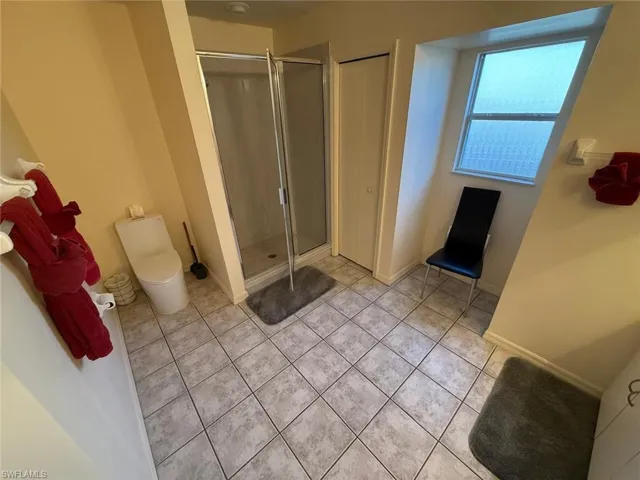 Full bath featuring a shower stall and light tile patterned floors
