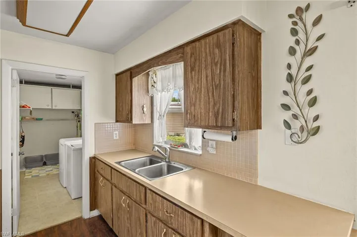 Kitchen with separate washer and dryer, decorative backsplash, light countertops, and brown cabinetry