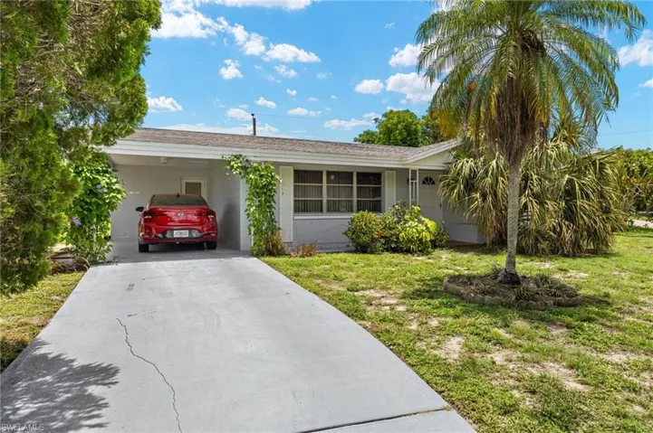 Single story home featuring a front yard, concrete driveway, an attached carport, and stucco siding