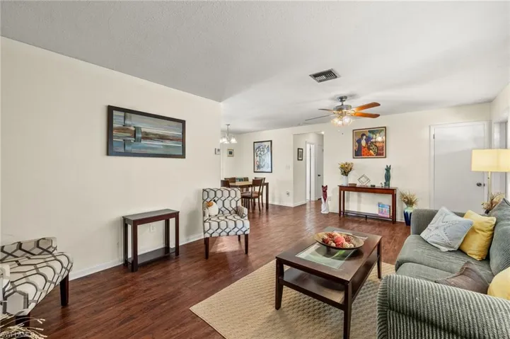 Living area with dark wood-style flooring, a ceiling fan, and a textured ceiling