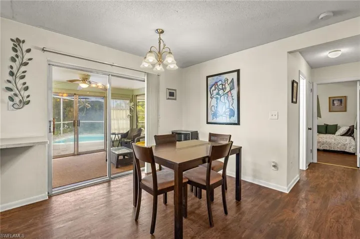 Dining room with wood finished floors, a chandelier, and a textured ceiling