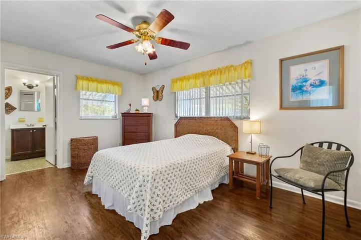 Bedroom with dark wood-style floors, connected bathroom, and a ceiling fan