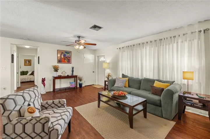 Living area with a textured ceiling, wood finished floors, and a ceiling fan