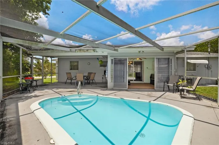 Swimming pool with a patio area, glass enclosure, and outdoor dining area