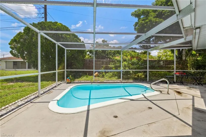 View of swimming pool with glass enclosure, a patio area, and a fenced backyard