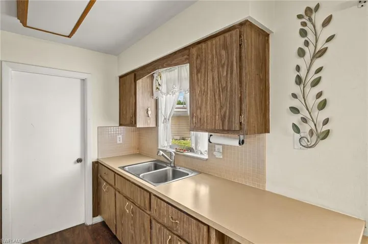 Kitchen featuring light countertops, backsplash, brown cabinets, and dark wood finished floors