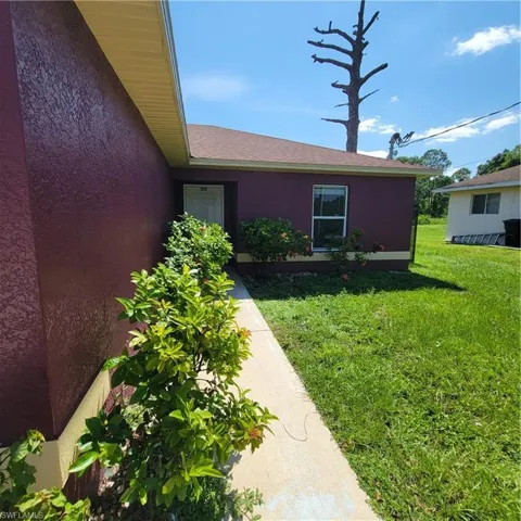 Doorway to property featuring a lawn and stucco siding