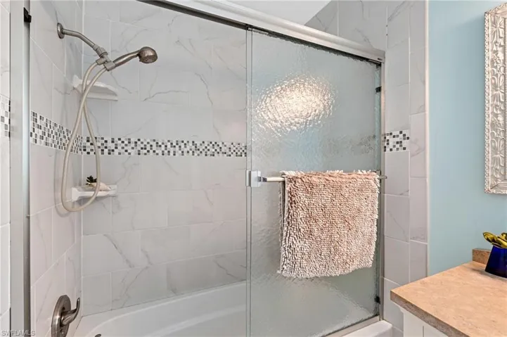 Bathroom featuring vanity and combined bath / shower with glass door