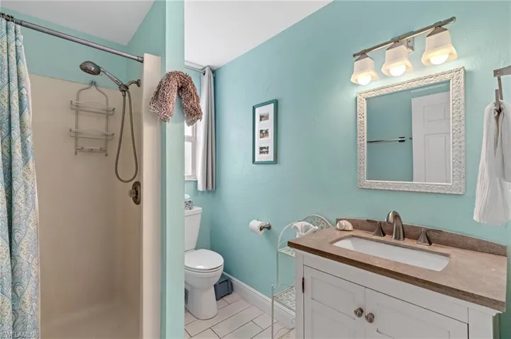Bathroom featuring vanity, curtained shower, and toilet