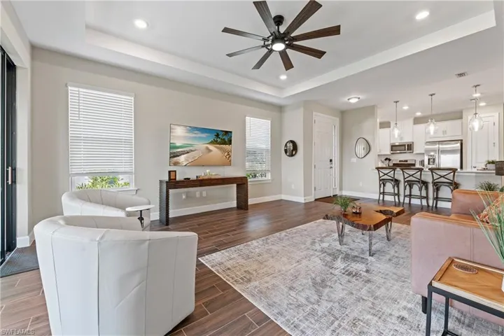 Open-concept living area featuring wood-finish tile flooring and a tray ceiling with recessed lighting