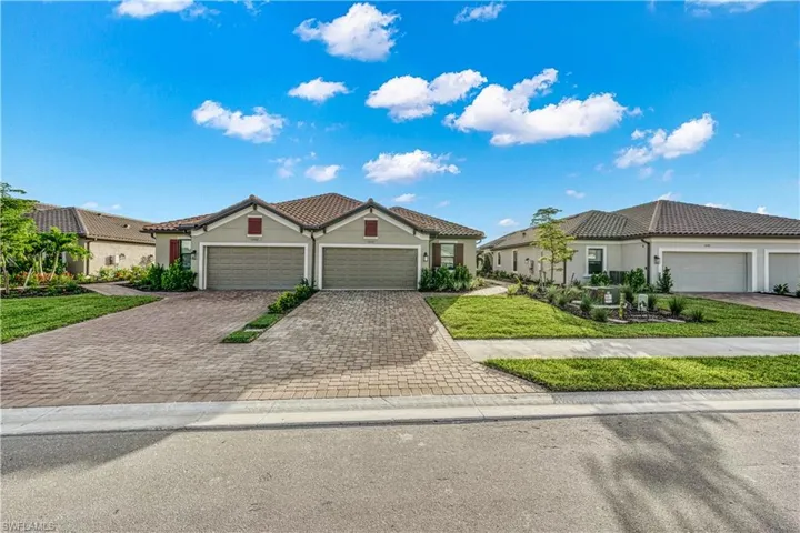 Paver driveways provide curb appeal to these stucco homes, each featuring a two-car garage and tiled roof