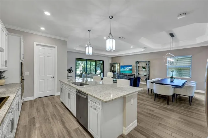 Kitchen with a raised ceiling, sink, white cabinetry, and light wood-type flooring