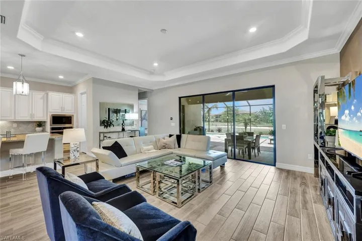 Living room featuring a tray ceiling, ornamental molding, and light hardwood / wood-style floors
