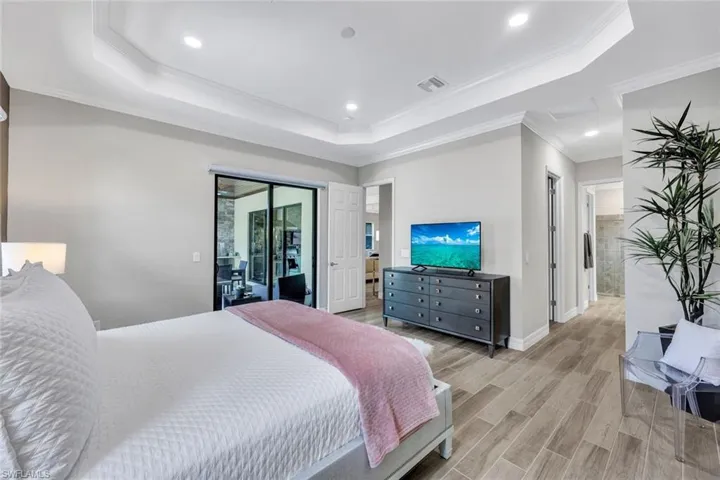 Bedroom with crown molding, access to exterior, light wood-type flooring, and a raised ceiling