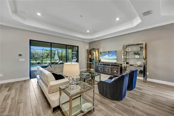 Living room with ornamental molding, a tray ceiling, and light wood-type flooring