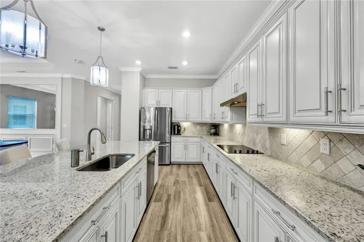 Kitchen with sink, ornamental molding, light wood-type flooring, and backsplash