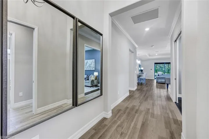 Hallway with light hardwood / wood-style flooring and crown molding