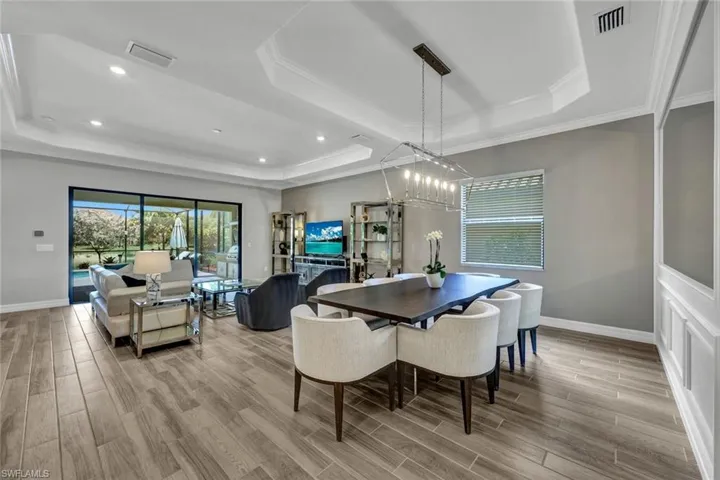 Dining space with a chandelier, a tray ceiling, light wood-type flooring, and ornamental molding