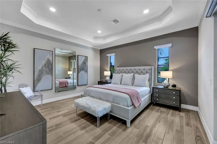 Bedroom with a tray ceiling, ornamental molding, and wood-type flooring