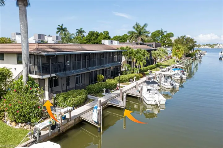 Waterfront property featuring multiple boat slips, a long private dock, screened-in balconies, tropical landscaping, and tile roofing