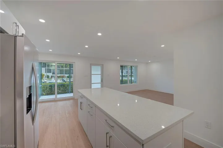 Kitchen island featuring a light-toned countertop and white cabinetry with stainless steel pulls