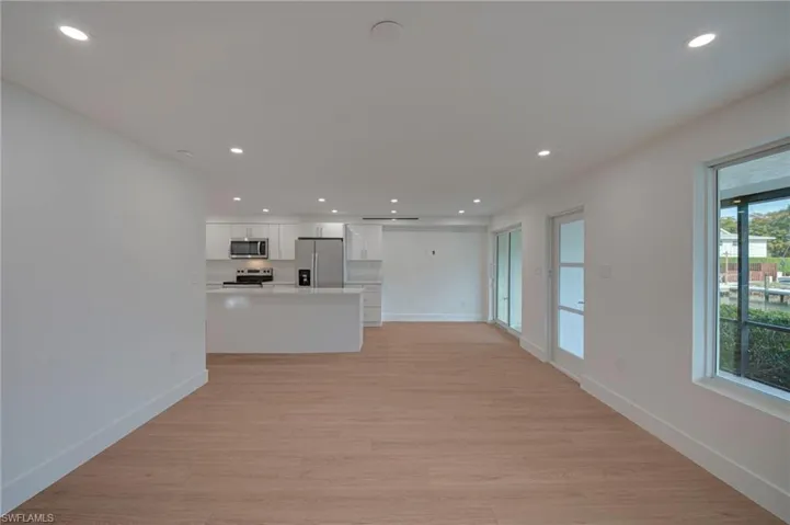 Open-concept living area featuring wood-finish flooring, recessed lighting, and white walls