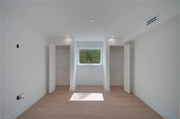 Bright room featuring light wood-finish flooring, recessed lighting, and a window with exterior tree views