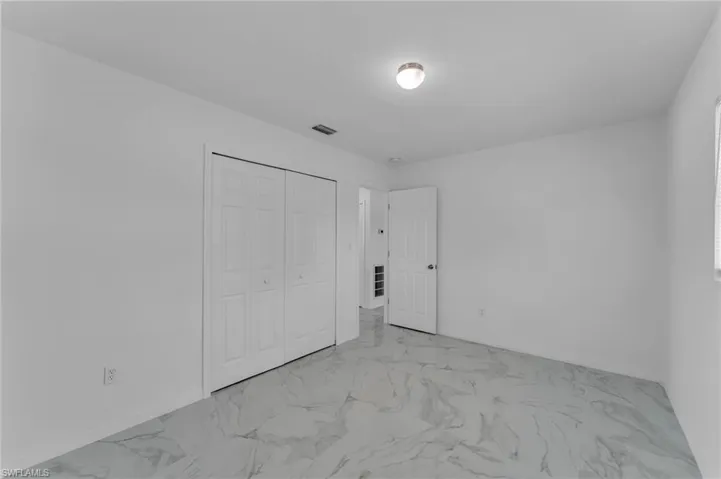 Unfurnished bedroom featuring a closet and light marble finish flooring