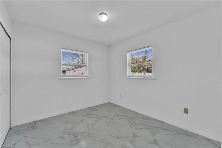 Unfurnished bedroom featuring a closet and light marble finish flooring