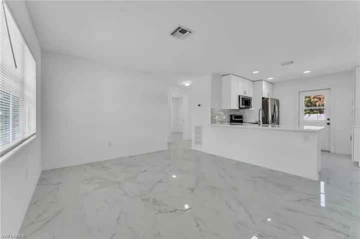 Unfurnished living room featuring baseboards and recessed lighting