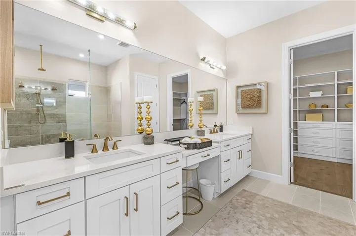 Full bath with a walk in closet, walk in shower, double vanity, and light tile patterned floors
