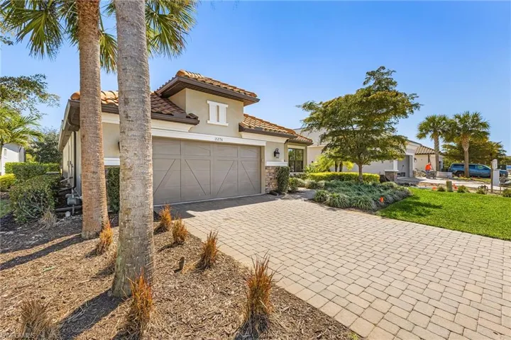 Mediterranean / spanish house featuring driveway, stucco siding, a tiled roof, stone siding, and a garage